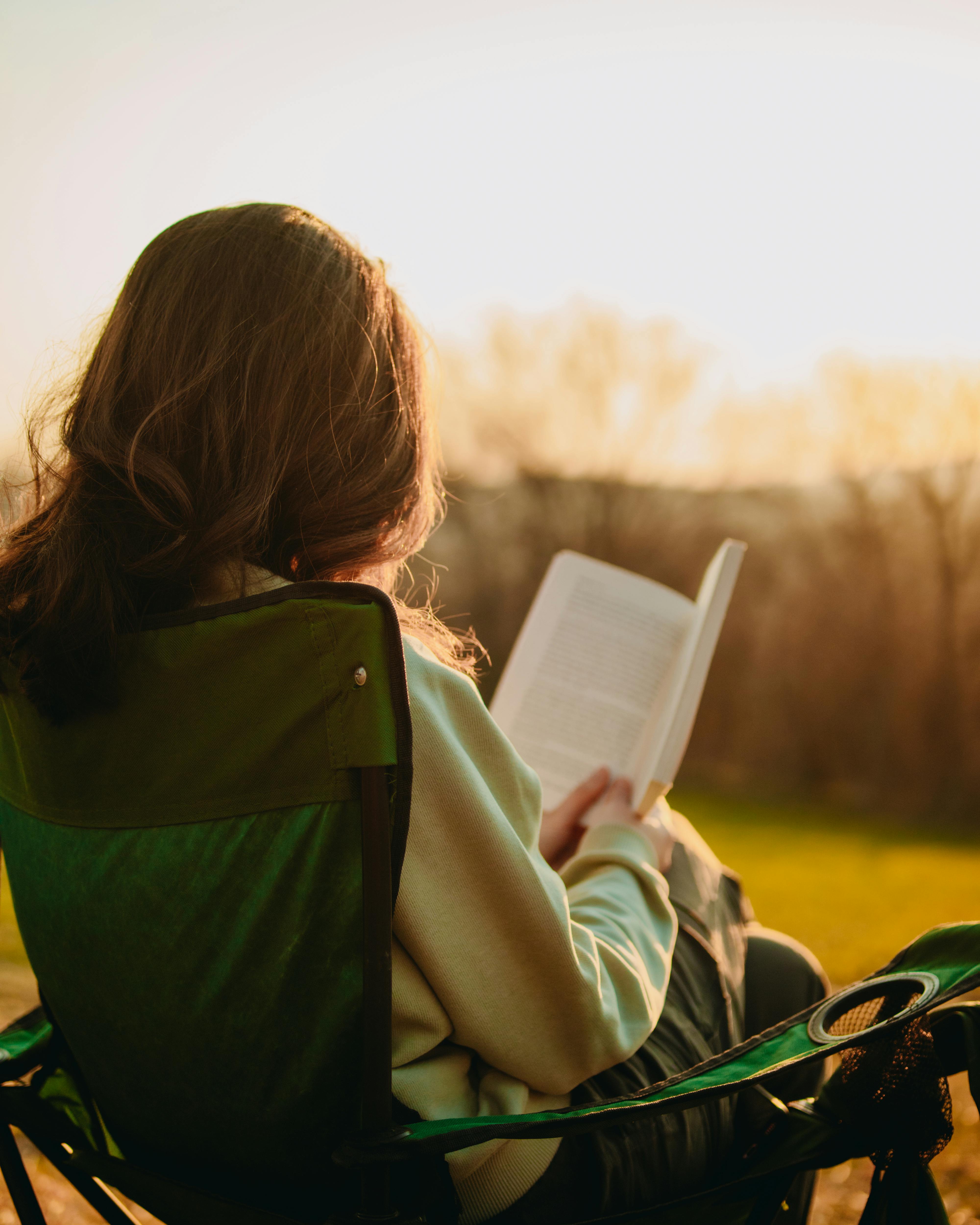 Woman reading outdoors in golden light — enjoying time freed up by remote work